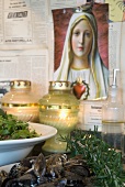 Mediterranean dishes and tea light holders in front of picture of the Madonna on wall