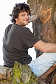 Smiling man carving heart in tree