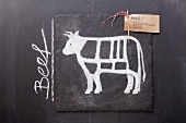 A sketch of a cow depicting cuts of meat with a label and the word 'Beef' drawn on a chalkboard