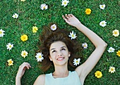 Woman lying on grass with flowers scattered around head