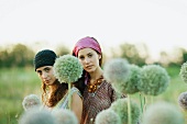 Young hippie women outdoors, allium flowers in blurred foreground