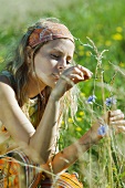 Young woman picking wildflowers in field, cropped view, close-up
