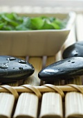 Wet stones, bamboo mat and dish containing vegetation