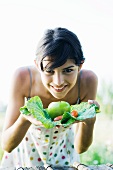 Young woman holding up fresh produce, smiling at camera
