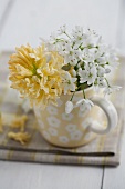 Posy of allium flowers & yellow hyacinth in mug