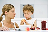 Mother and son preparing food together, boy holding apple, both looking down