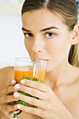 Woman drinking glass of vegetable juice, looking at camera