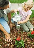 Man and girl watering flowers