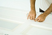 Man taping door with adhesive tape, cropped view of hands