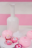 Stillleben in Weiß und Rosa mit Vase und Glasbehälter neben Desserts
