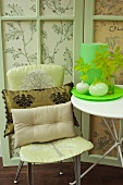 Side table and cushions on chair against patterned fabric screen