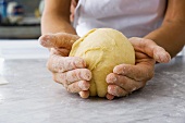 Hands shaping a ball of dough