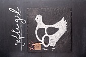 Gezeichnetes Huhn und Etikett mit Bezeichnung auf einer Schiefertafel
