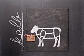 A sketch of a calf and a written label on a chalkboard
