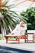 Woman in dressing gown relaxing by pool