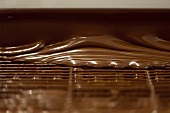 Schokolade zum Schokolieren von Pralinen fließt über Gitter