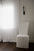 High back chair below candle sconce