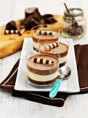 Tricoloured, layered chocolate desserts in glasses