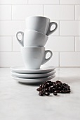 Small Pile of Coffee Beans; Three Stacked Espresso Cups and Saucers