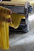 Tagliatelle being cut with a pasta machine