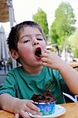 Kleiner Junge isst Schokoladeneis in einer Gelateria