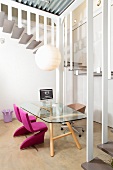 Simple glass table and chairs with pink upholstery in office with view of winding staircase