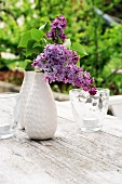 Purple lilac in vase on garden table
