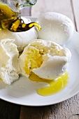 A ripped open ball of buffalo mozzarella being drizzled with extra virgin olive oil