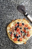 Pizza topped with gorgonzola and mozzarella cheese with cherry tomatoes and black olives