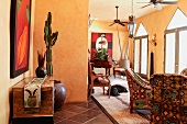 Rustikale Kommodel und Sessel mit folkloristischem Stoffbezug in offenem gelb getönten Wohnraum eines mexikanischen Landhauses