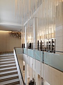 Grosszügige Treppenhalle mit Lichtobjekt aus hängenden Glasstäben an Decke