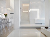 Offener, minimalistischer Wohnraum mit Essplatz und Blick in Vorraum mit Treppenaufgang in Weiß