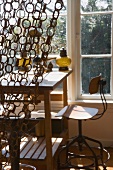 Curtain of linked bast-fibre rings in front of plain desk in front of window