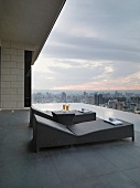 Modern outdoor loungers on roof terrace with view over cityscape