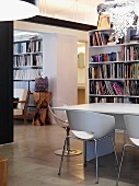 Retro Schalenstühle am Tisch vor Bücherregal in offenem Wohnraum