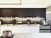Designer kitchen with white kitchen units and backlit shelf against dark-grey wall