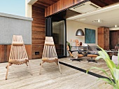 Outdoorstühle aus Holzlamellen auf Terrasse mit Steinboden und Blick in offenen Wohnraum