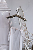 White nightgown on a rustic hanger on an antique chair