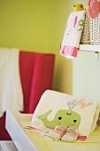 Handtuch mit Wahlfisch-Motiv und Babyschuhe auf einem Wickeltisch