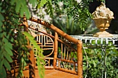 Stuhl aus Bambus neben Vintage Gartentisch mit Pflanzengefäss aus Stein