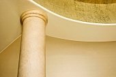Ausschnitt eines Säulenkapitells unter kreisförmiger Wandscheibe mit vergoldeter Oberfläche