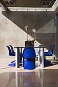 Blaue Schalenstühle am Tisch auf gefliester Terrasse im Designerstil