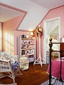 Ornaments on white shelves in child's bedroom with pink wallpaper and white wicker rocking chair