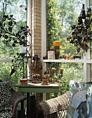 Corner of glazed veranda in the country with vintage table, wicker chairs and terracotta ornaments