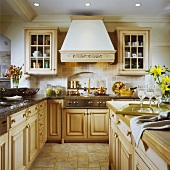 Nostalgic country-house kitchen with light wooden furniture and chimney-breast-style extractor hood
