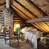 Rustic attic bedroom with old beamed ceiling, wood and brick wall and patterned cushions and blankets on a single bed