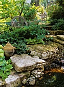 Lauschige Gartentreppe zwischen einem Wasserlauf und Funkien