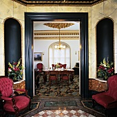 Polygonal hall with marble tiled floor, bouquets in niches, brocade armchairs and view into fine dining room
