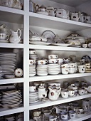 Weisses Wandregal mit einer großen Sammlung edlen Geschirrs