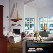 Large windows and large model sailing boat above open fireplace in living room